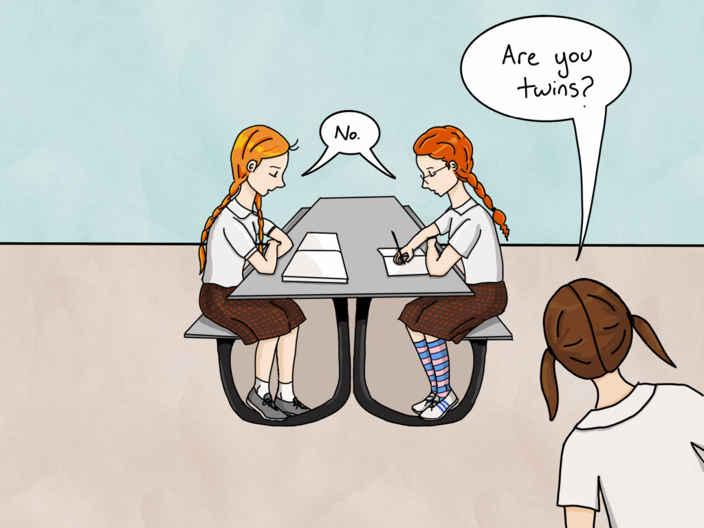 The same scene, with two red-haired girls sit at a table. The other student leans into the picture from the other side and asks again, "Are you twins?" The redheads respond "no" together.