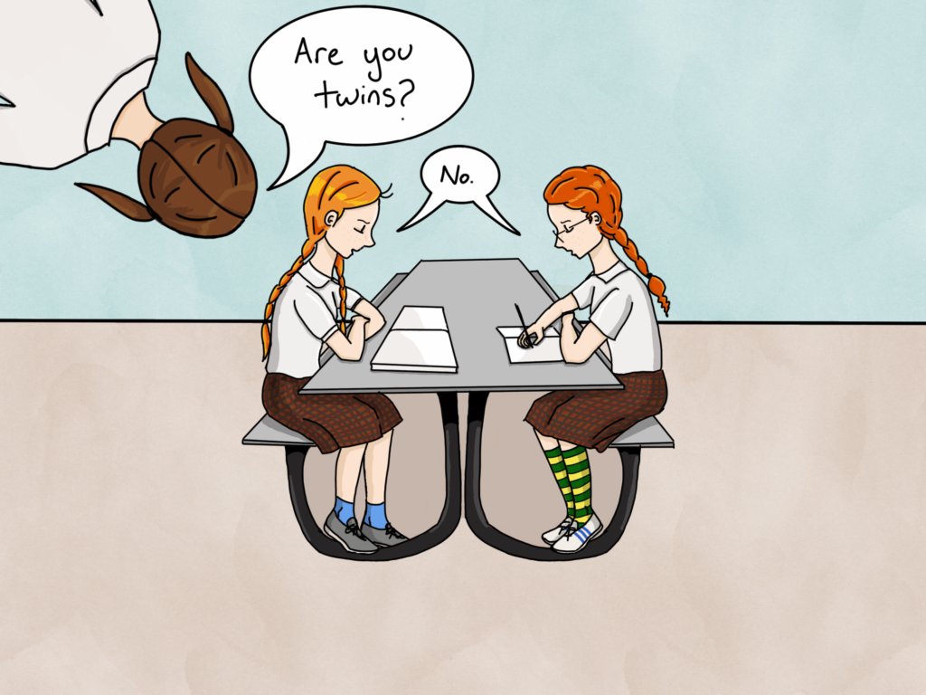 The same scene again, with the two red-haired girls sitting at a table. The other student leans into the picture from the top and asks again, "Are you twins?" The redheads respond "no" together.